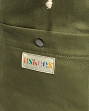 Close-up view of Uskees logo and external pocket of the moss-green #0402 bucket bag.