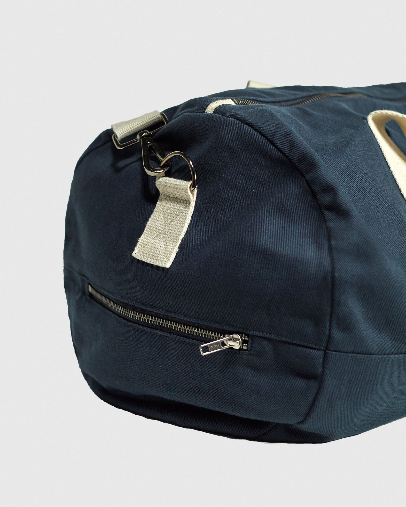 Focus on end of Uskees #0403 barrel bag in bluberry cotton drill, showing end zipper pocket and cotton webbing carry handle attachment.