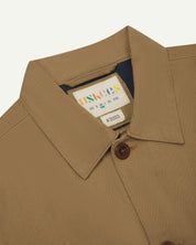 Close-up view of collar and brand label of a khaki buttoned 3003 workshirt for men from Uskees. 