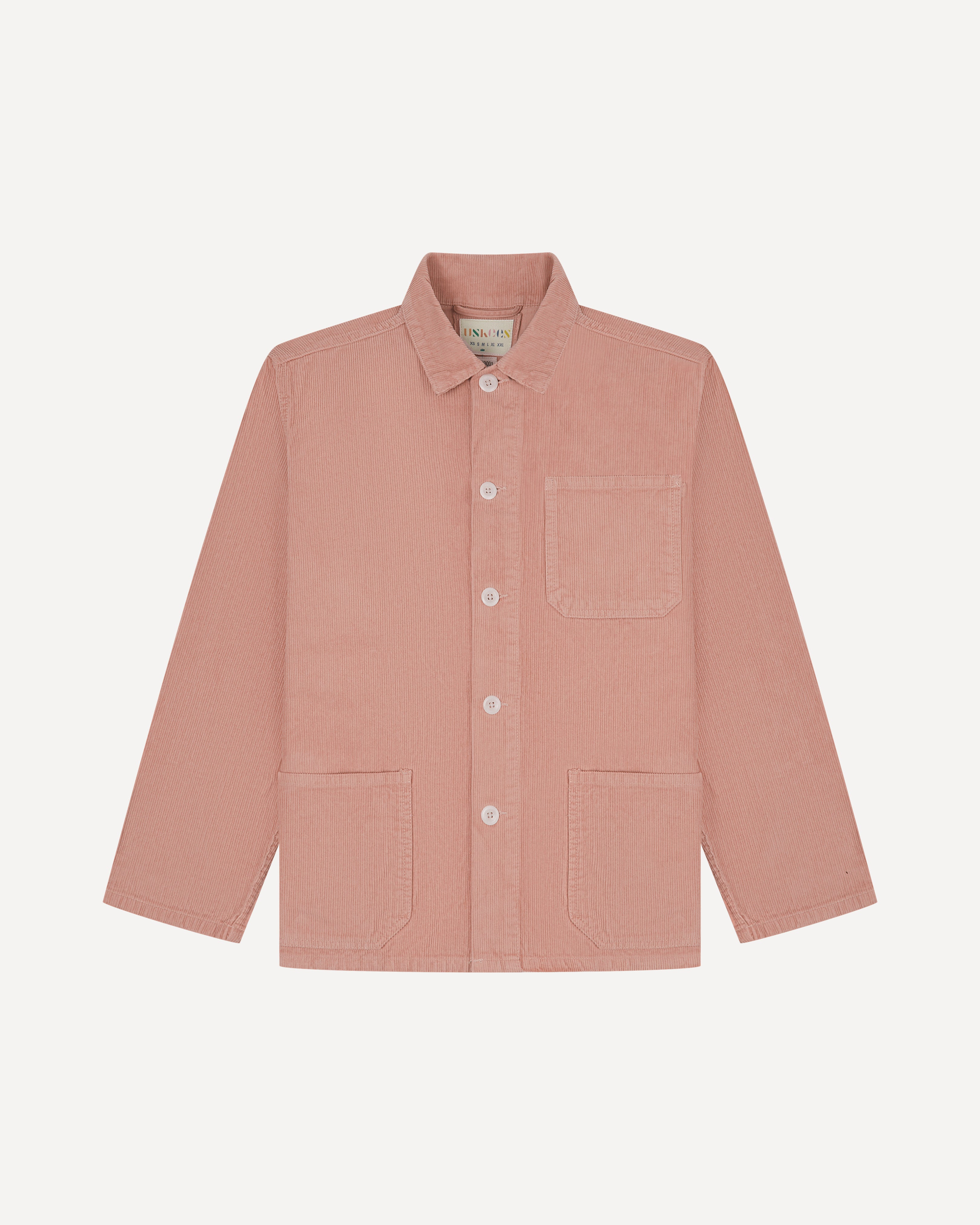 Front flat shot of pale pink, buttoned corduroy overshirt from Uskees. Clear view of corozo buttons, chest and hip pockets.