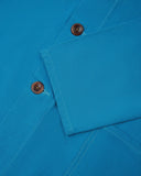 Closer view of mid section of bright blue, buttoned organic cotton overshirt from Uskees. Focus on cuff, pockets and corozo buttons.