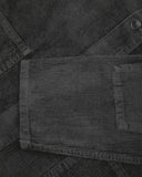 Closer view of mid section of charcoal-grey, buttoned corduroy overshirt from Uskees. Focus on cuff, pocket, corozo button and corduroy texture.
