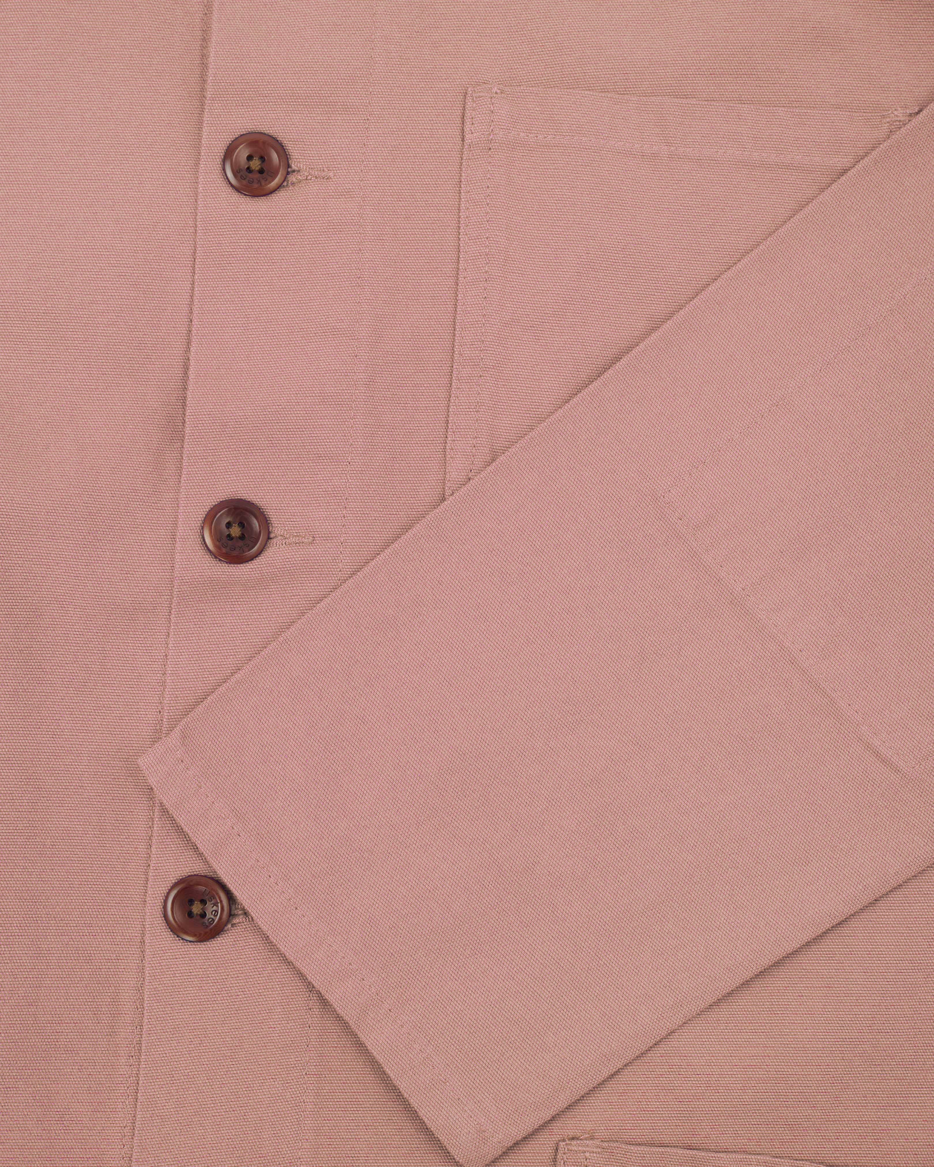 Front flat close shot of an uskees pale pink men's overshirt showing corozo buttons and sleeve/cuff detail.