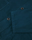Closer view of mid section of petrol blue, buttoned corduroy overshirt from Uskees. Focus on cuff, pockets, corozo buttons and corduroy texture.