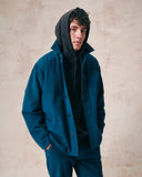 Male model wearing petrol blue, buttoned corduroy overshirt unbuttoned over an uskees hooded sweatshirt.