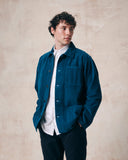 Male model wearing petrol blue, buttoned corduroy overshirt unbuttoned. Clear view of chest and hip pockets, corozo buttons.