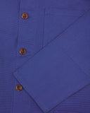 Closer view of mid section of ultra blue, buttoned organic cotton overshirt from Uskees. Focus on cuff, pockets and corozo buttons.