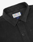 Close-up view of 3001 charcoal-grey, buttoned corduroy overshirt from Uskees showing corozo buttons, brand/size label, collar and hanging hoop.