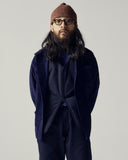Male model wearing a navy corduroy shacket and brown speckled beanie on a plain grey background