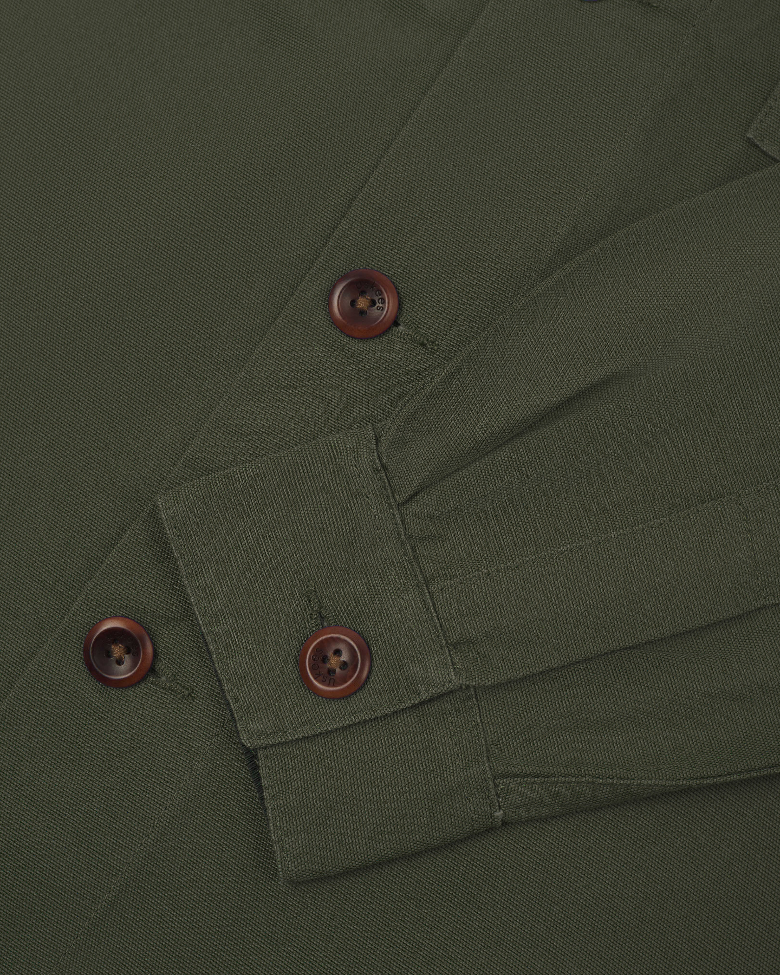 Close-up shot of dull green #3003 men's workshirt from Uskees. Showing cuff/sleeve and corozo buttons.
