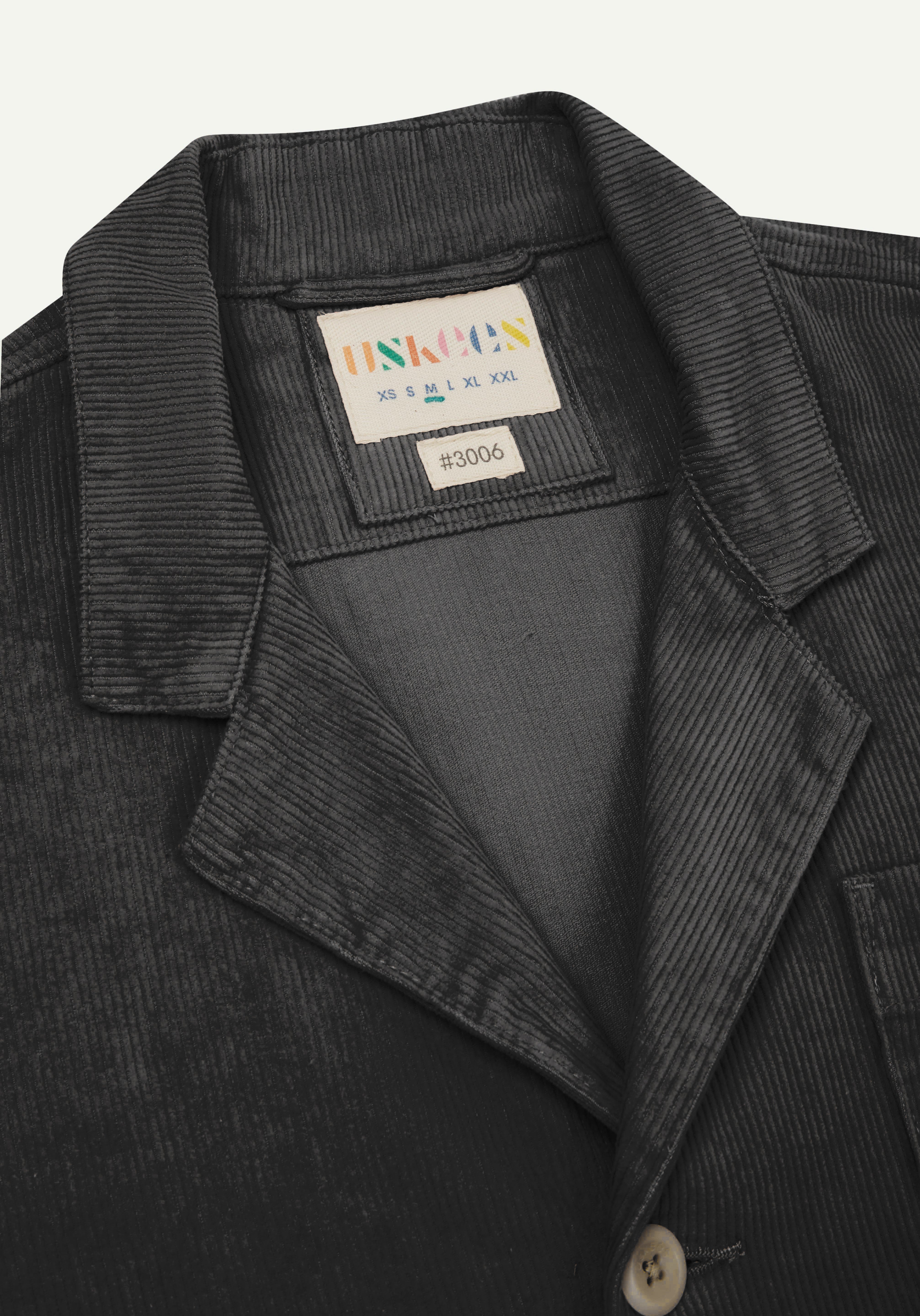 Flat front close view of dark grey #3006 corduroy blazer with view of collar, brand/size label and Uskees branding label.