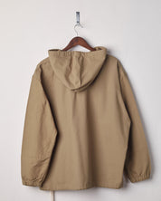 Back view of khaki coloured buttoned smock from Uskees with view of hood. Presented on hanger with white backdrop.