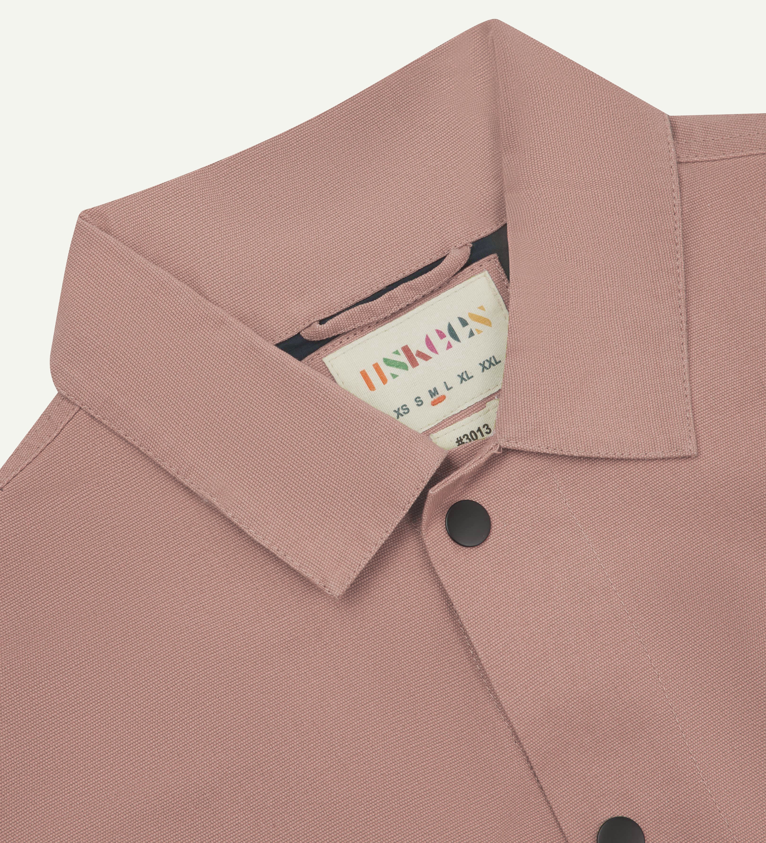 Close up shot of Uskees #3013 dusty pink coach jacket showing neck label and popper fastening