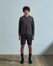 Full-length front view of model wearing #3028 charcoal-grey organic canvas vest paired with dark shorts. Half zipped to demonstrate double-ended YKK zip.