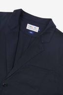 Close-up and angled front view of the 3047 docklands blazer showing the twill fabric texture, collar, lapel, Uskees branding label and jetted breast pocket.