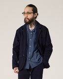 Front view of a bearded male model wearing the Uskees midnight blue docklands jacket, matching trousers and a blue shirt.
