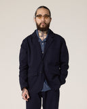 Front view of a bearded model wearing the Uskees midnight blue docklands jacket, matching trousers and a blue chambray shirt.