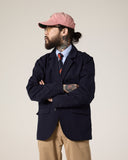 Front view of a bearded male model looking to the right wearing the Uskees midnight blue docklands jacket, khaki trousers and a pale blue shirt.