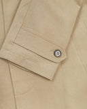 Close-up of an Uskees beige car coat sleeve and cuff with a button