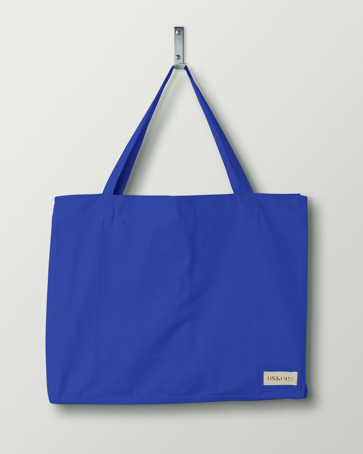 Full front hanging shot of Uskees #4001 large ultra-blue tote bag, showing double handles and Uskees woven logo.