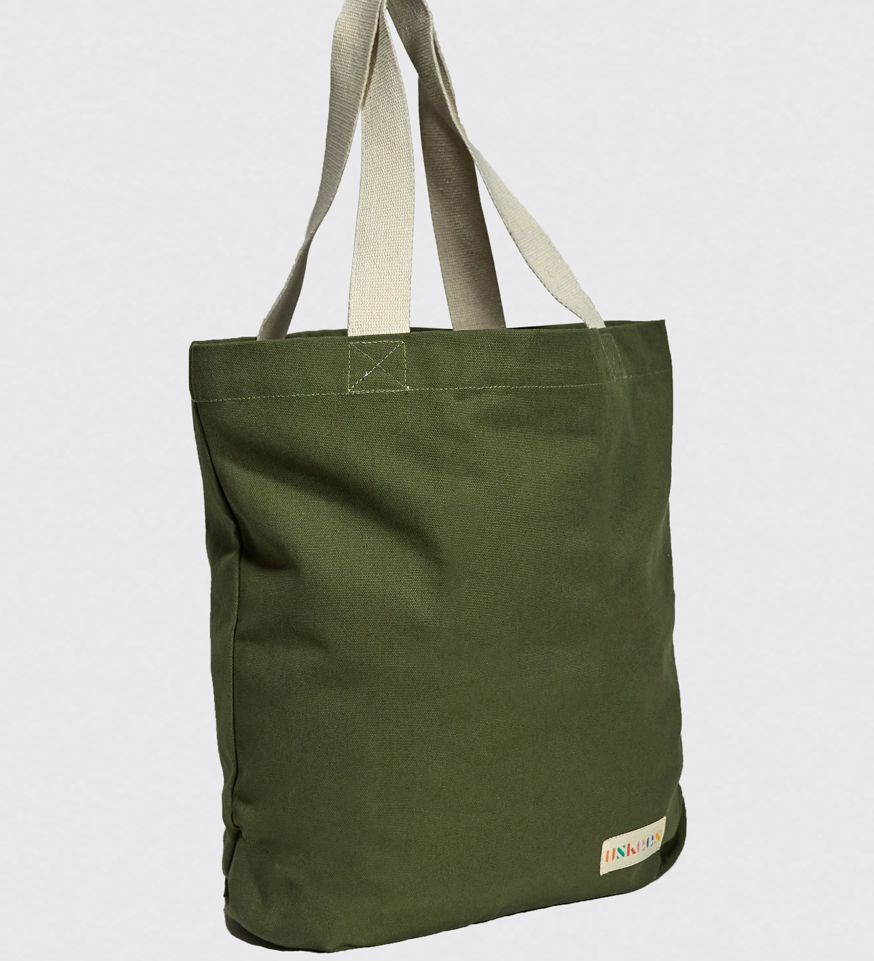 Slightly angled front view of Uskees #4009 'coriander' coloured canvas tote bag, showing double webbing straps and Uskees woven logo.