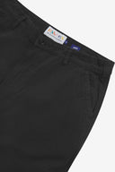 Close up of waist area of twill workwear pants in black. Clear view of front pocket, Corozo button fastening, Uskees branding label and organic cotton twill weave.