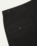 Close-up reverse view of Uskees charcoal-grey corduroy work pants with focus on left rear flap pocket, belt loops and adjustable button waist.