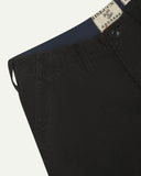 Close-up front view of left front pocket, belt loops, triple stitching, and Uskees branding label. Also a closer view of the organic, 11 wale corduroy in charcoal-grey.