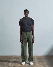 Full length front-view of model wearing coriander-green cotton 5014 trousers with view of belt loops, cargo pockets and Corozo buttons.