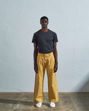Full-length front view of model wearing Uskees #5018, citronella yellow mid-weight cotton boat pants paired with faded black t-shirt.