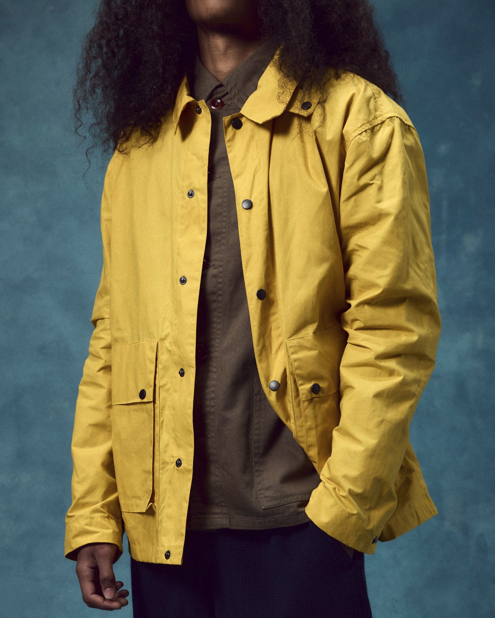 Front view wearing the Uskees wax storm jacket in British yellow. Jacket open, clearly showing the contrasting popper fastenings.