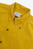 Angled close-up view of the #7001 wax storm jacket with focus on the storm collar, Uskees branding label and contrasting popper fastenings.