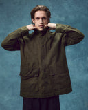 Front view of man wearing the Uskees wax storm jacket in dark 'Pennine' green. Jacket fastened, clearly showing the large flap pockets and storm collar.