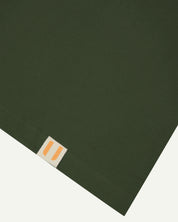 Front close view of hem - mid-green oversized  organic cotton T-shirt by Uskees showing the brand logo.