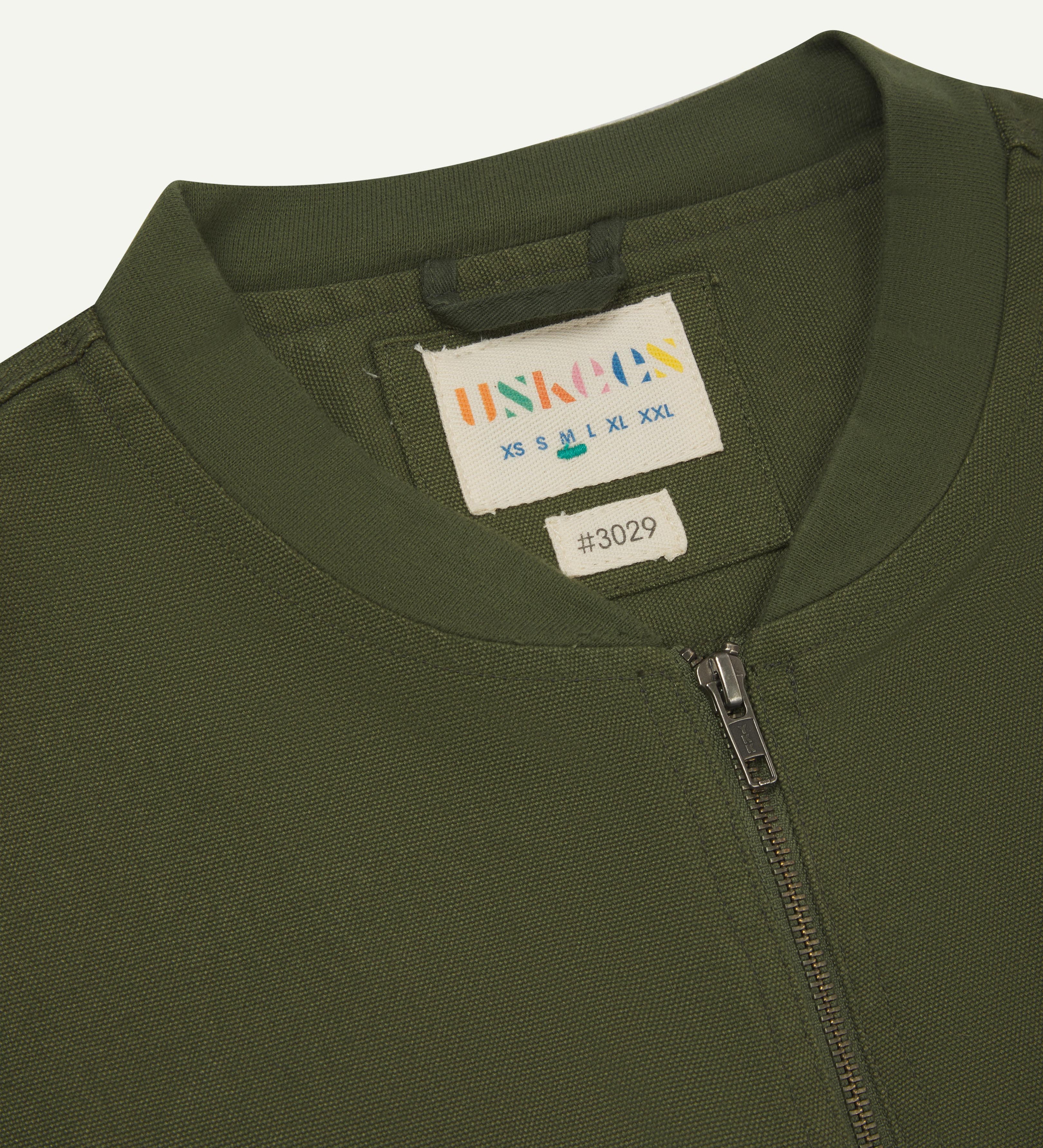 close-up flat shot of uskees green gilet-type zip front waistcoat showing neck, zip and inner brand label at neck