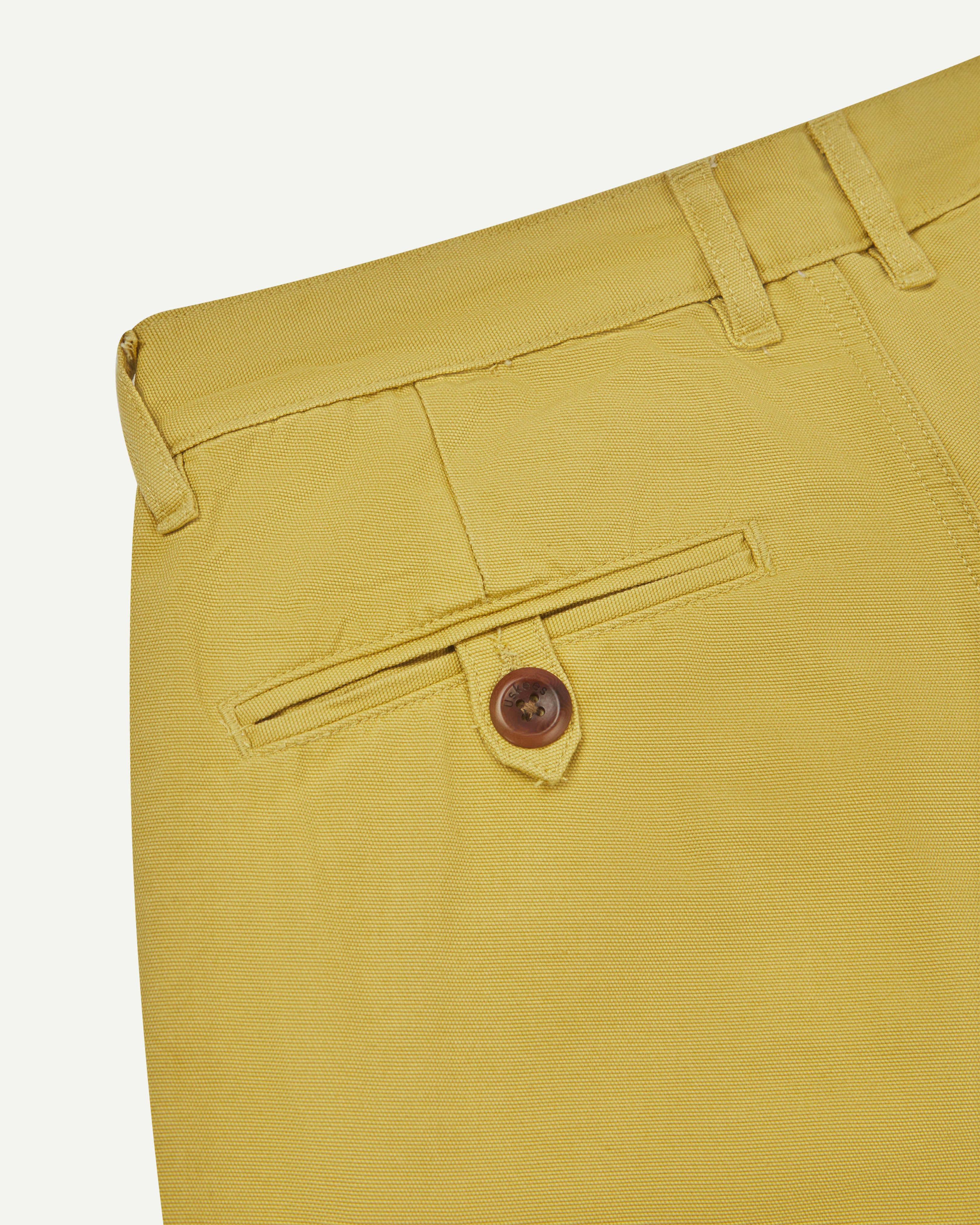 Back close-up view of #5018 Uskees men's organic mid-weight cotton boat trousers in acid yellow showing belt loops and buttoned back pocket.