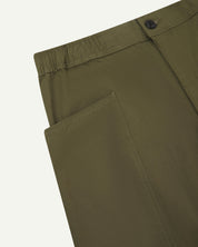 Close angled view of the elasticated waist and corozo button fastening of the olive green #5011 Uskees pants.