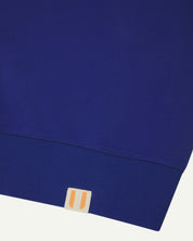 Close up view of bright blue men's organic heavyweight cotton #7005 sweatshirt showing uskees logo label on hem.