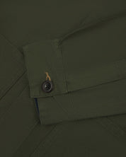 Front close up view of uskees men's dark green overshirt with hidden buttons showing buttoned cuff, sleeve and pockets.