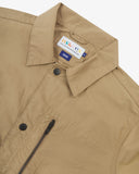 Front close up view of Uskees beige ripstop utility jacket with black poppers and zipped pockets showing the brand label.