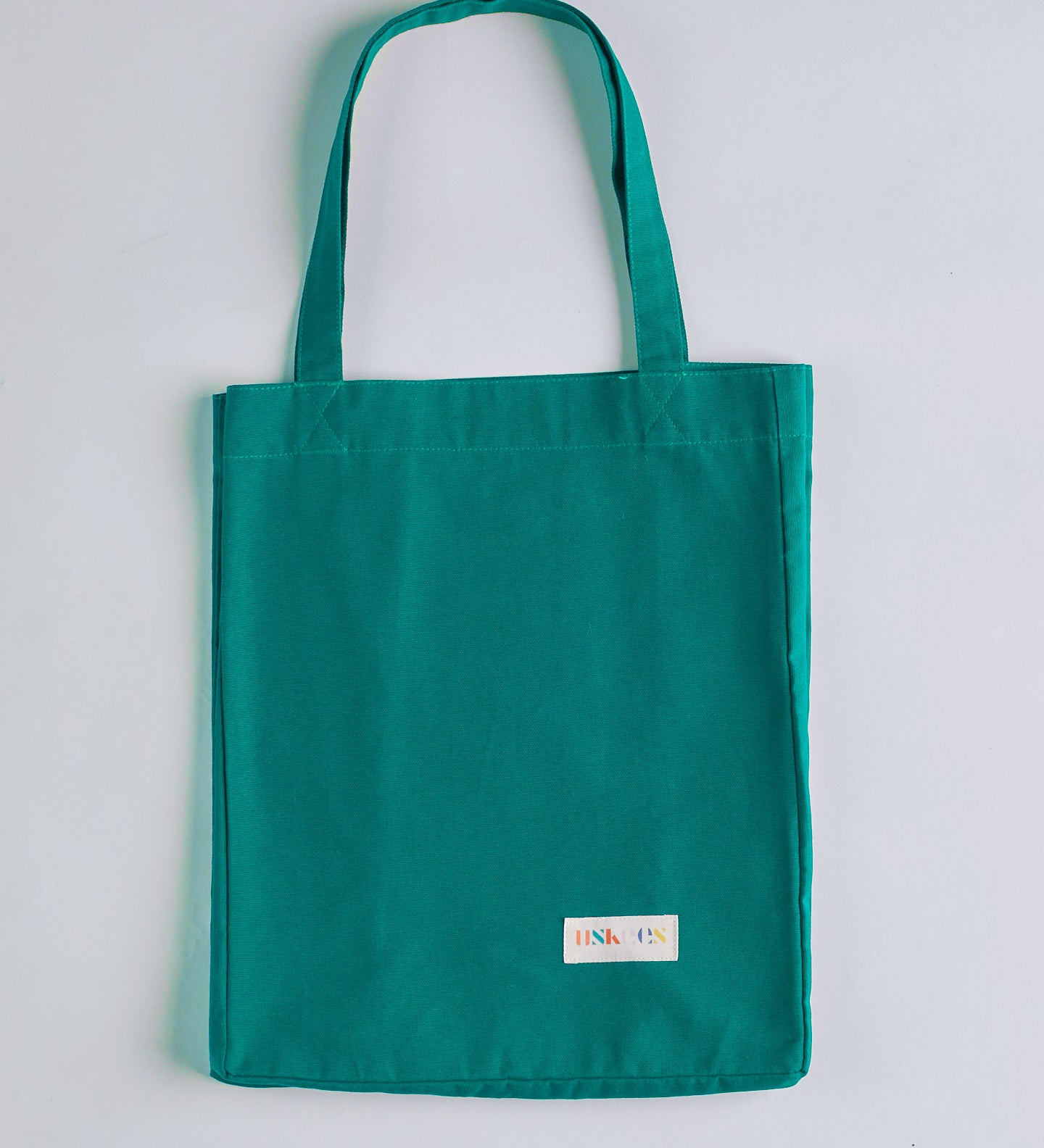 Full front hanging shot of Uskees #4002, small 'foam green' tote bag, showing double handles and Uskees woven logo.