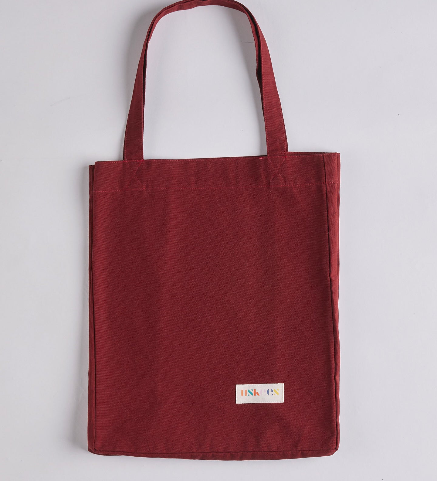 Full front flat shot of Uskees #4002, small 'merlot' tote bag, showing double handles and Uskees woven logo.