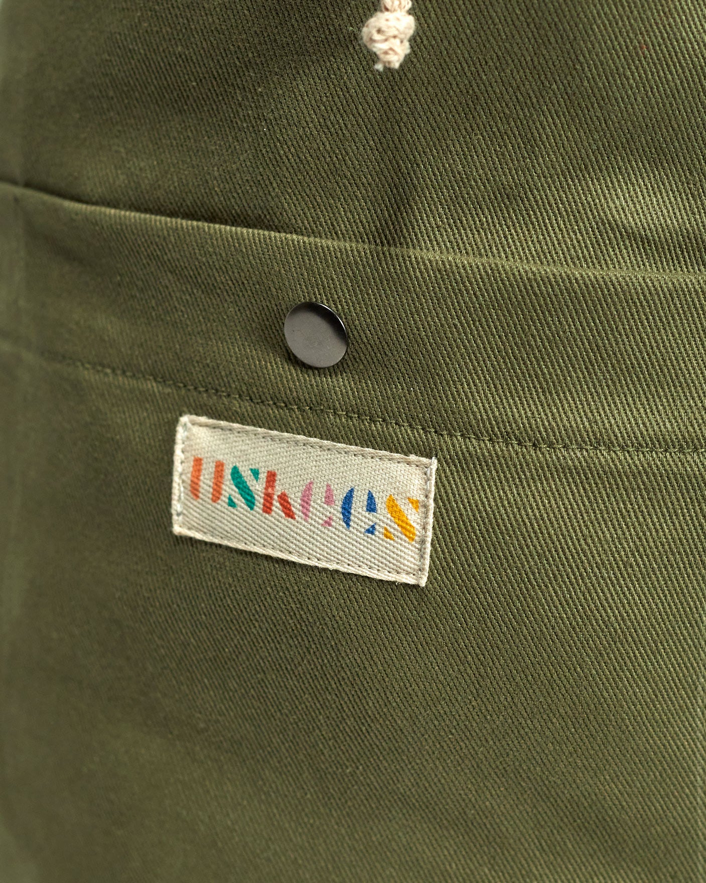 Close-up view of Uskees logo and external pocket of the moss-green #0402 bucket bag.