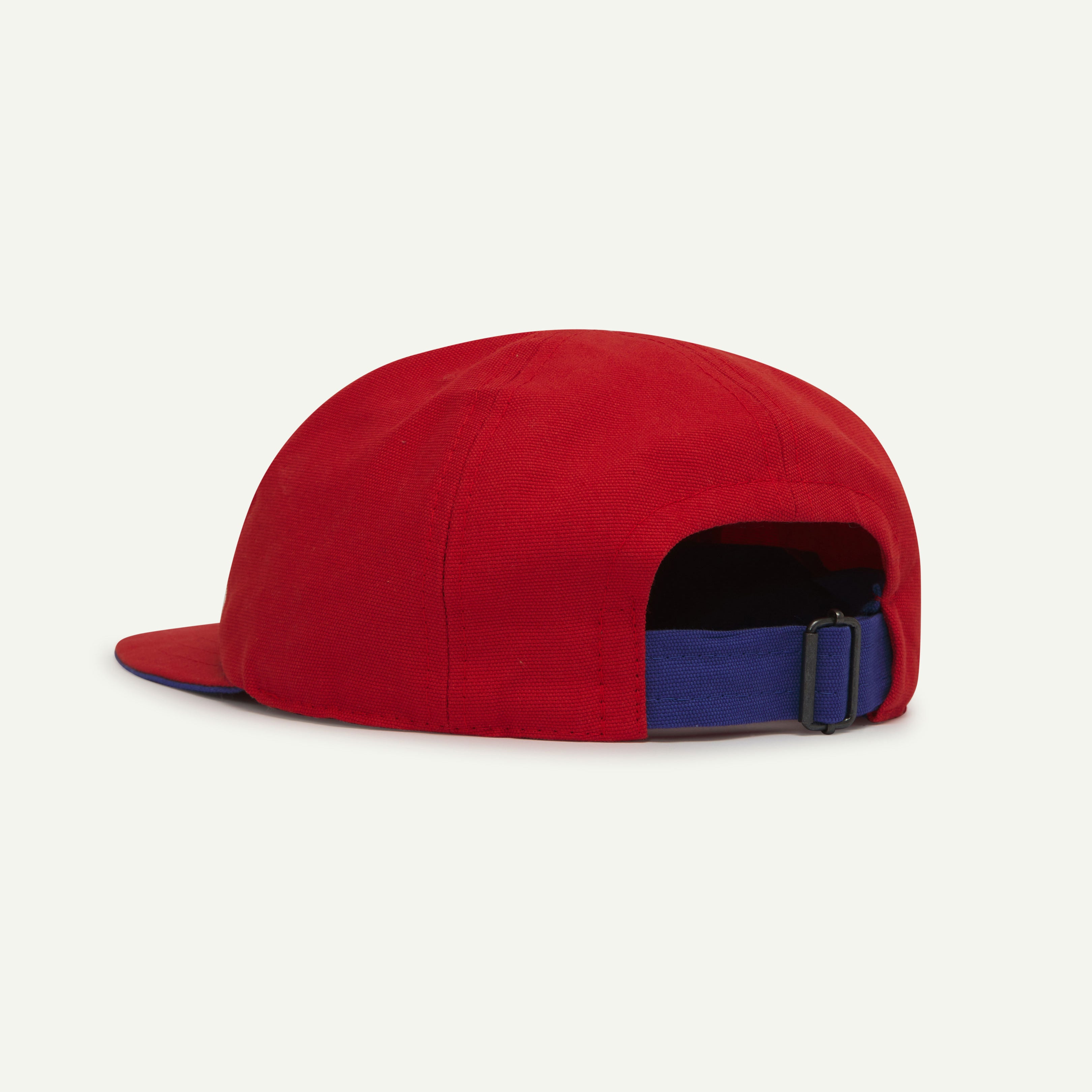 Angled back view of Uskees deadstock 6-panel cap in bright red showing contrast blue adjuster loop.