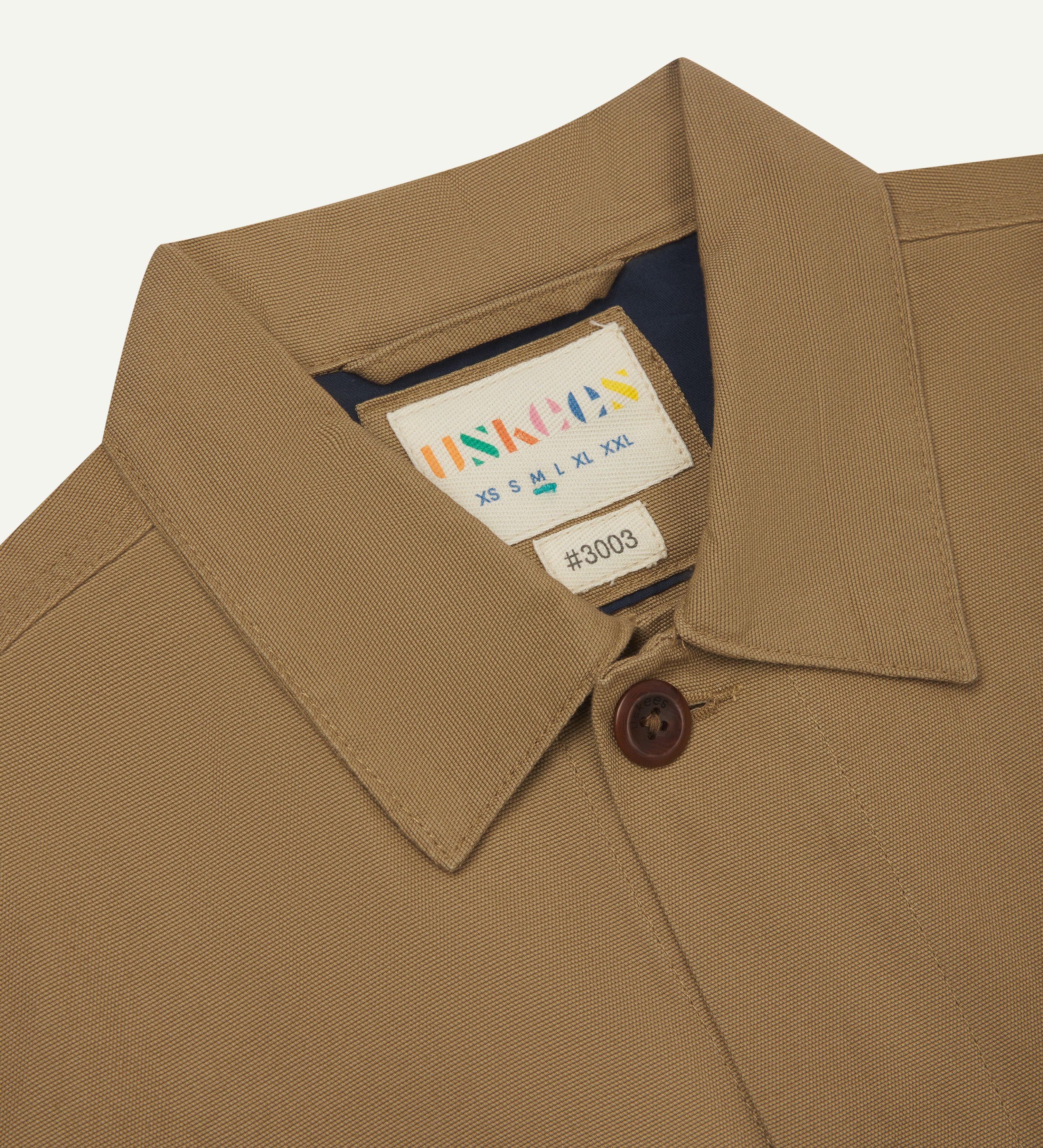 Close-up view of collar and brand label of a khaki buttoned 3003 workshirt for men from Uskees. 