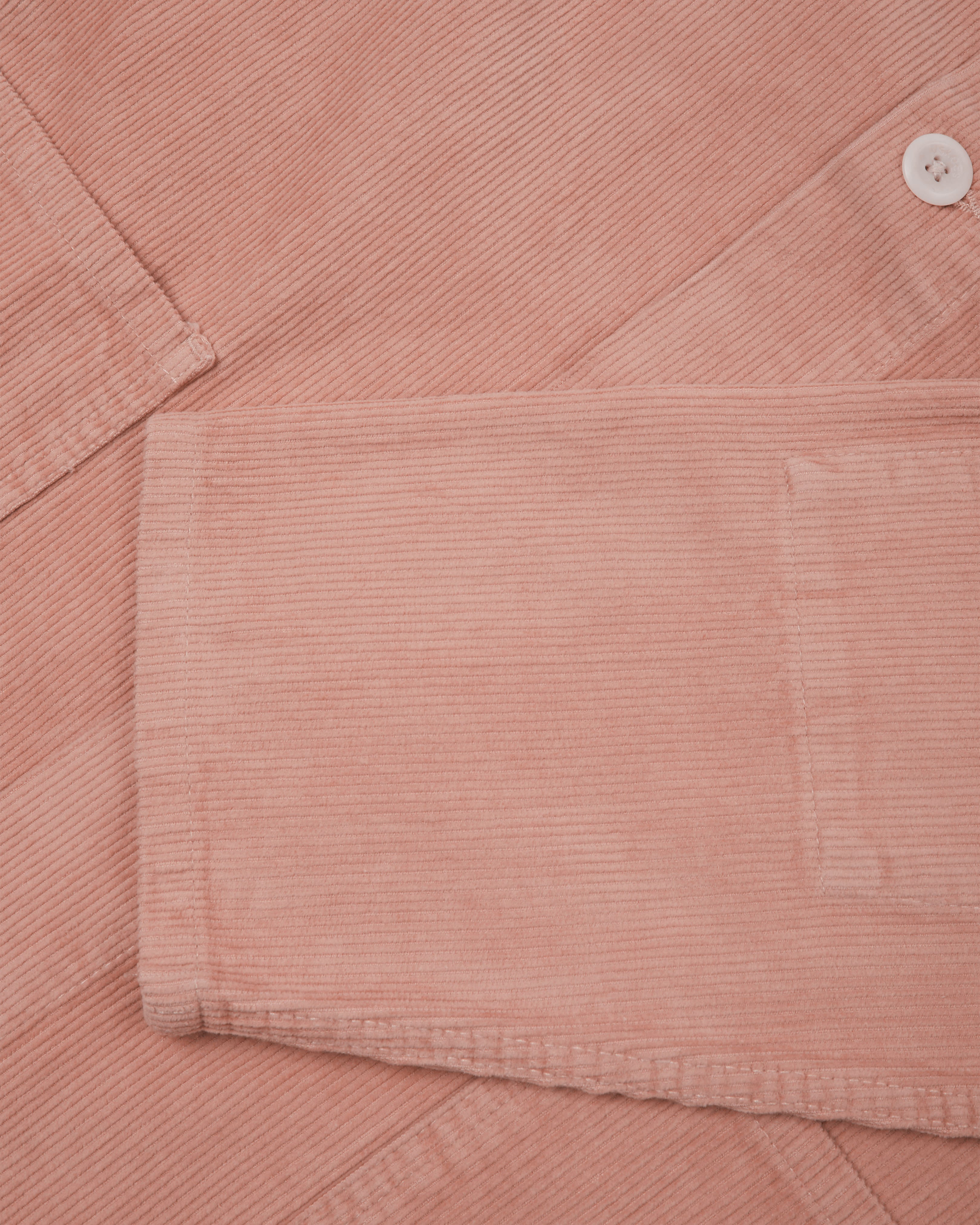 Close-up shot of pale pink, buttoned corduroy overshirt from Uskees. Showing sleeve detail and corozo buttons, 