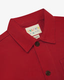 Close-up view of 3001 berry red, buttoned organic cotton overshirt from Uskees showing corozo buttons, branding label, collar and hanging loop.