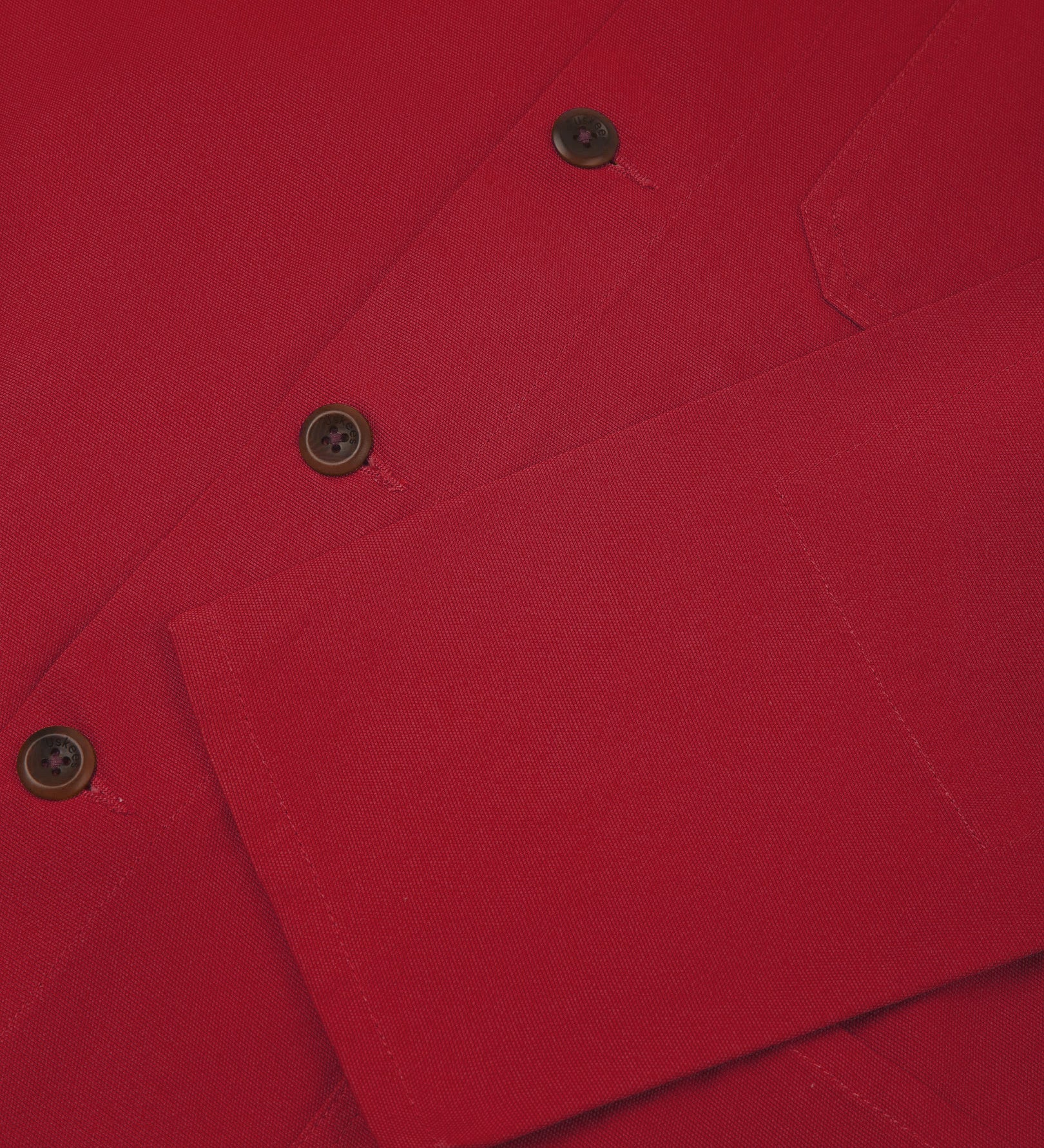 Closer view of mid section of berry red, buttoned organic cotton overshirt from Uskees. Focus on cuff, placket and corozo buttons.