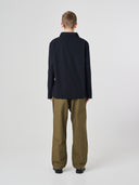 Full-length back view of man wearing an Uskees black ripstop overshirt paired with dark pants, showing reinforced elbows.