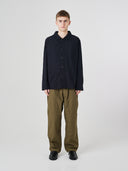 Full-length view of man wearing an Uskees black ripstop overshirt paired with green  pants.